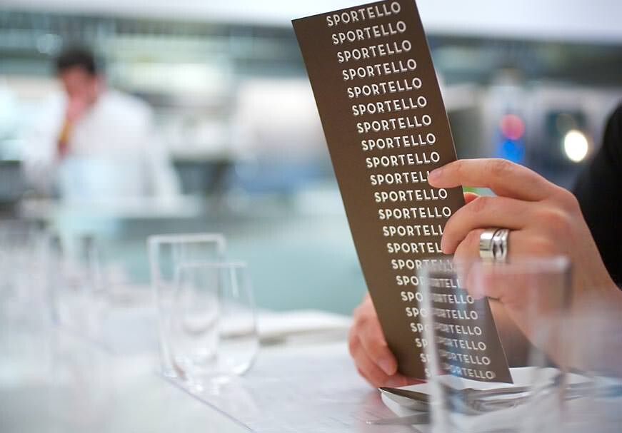 Customer reads a Sportello menu at a table