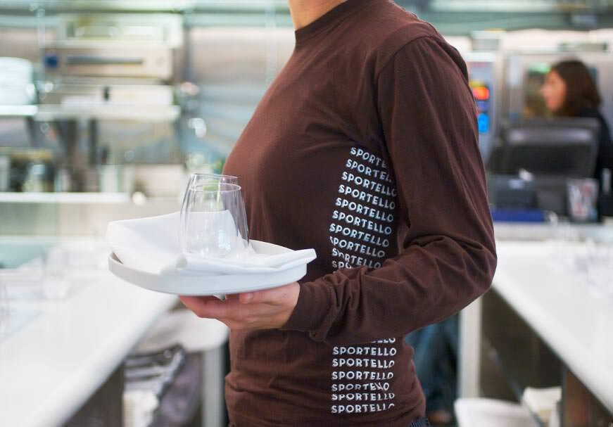 Waiter in a long sleeve shirt with repeating Sportello pattern
