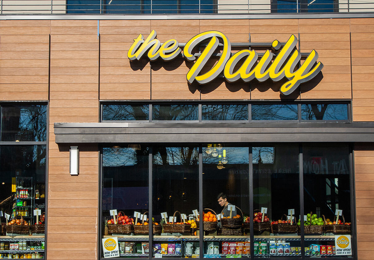 The Daily exterior straight-on shot of market with fruits in window.