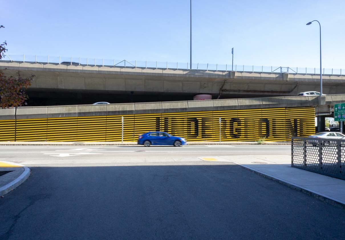A blue car drives in front of the painted Underground mural